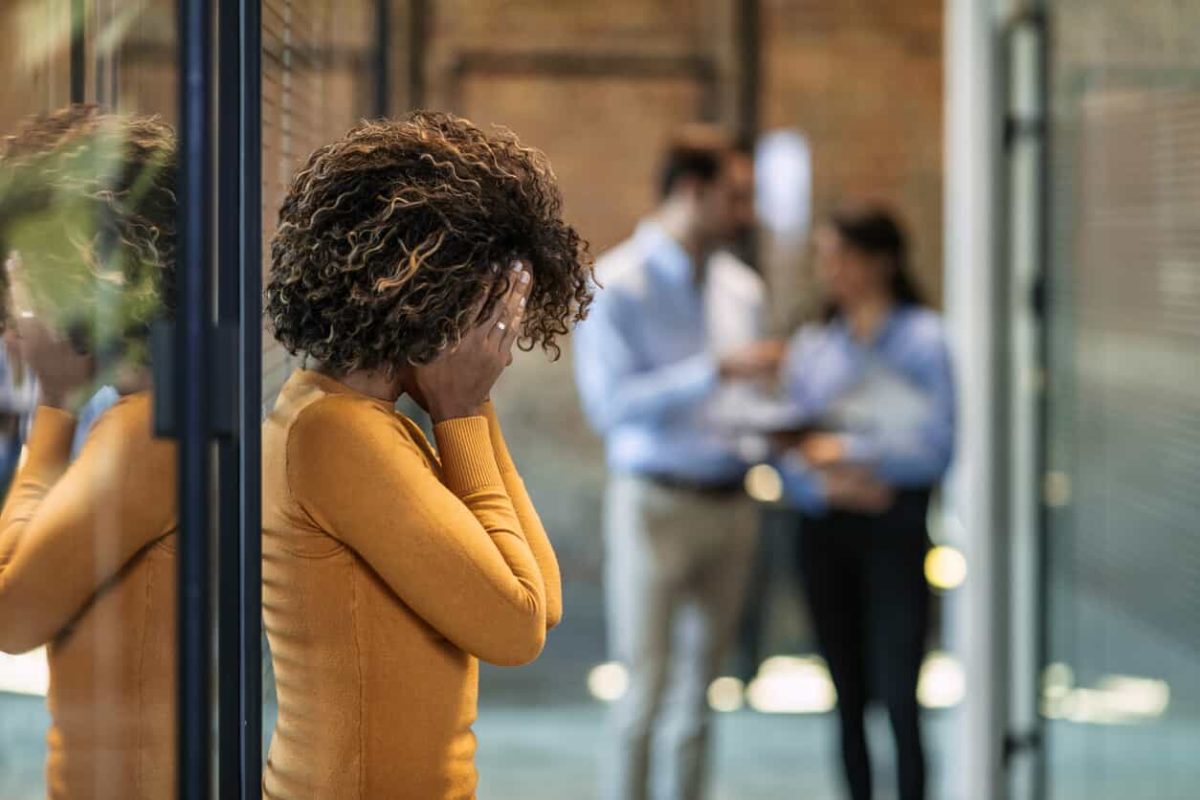 Black woman with her hands over her face at work